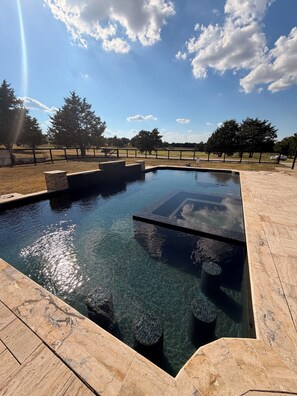 A clear swimming pool with stone steps and a metal railing, surrounded by a paved area and trees. - Perfect 6-bedroom barn with Pool in lovely McKinney (McKinney)