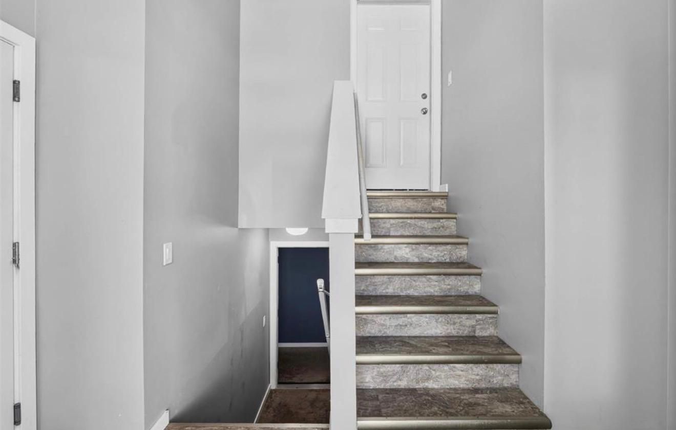 A staircase with a white door at the top and a dark-colored wall.