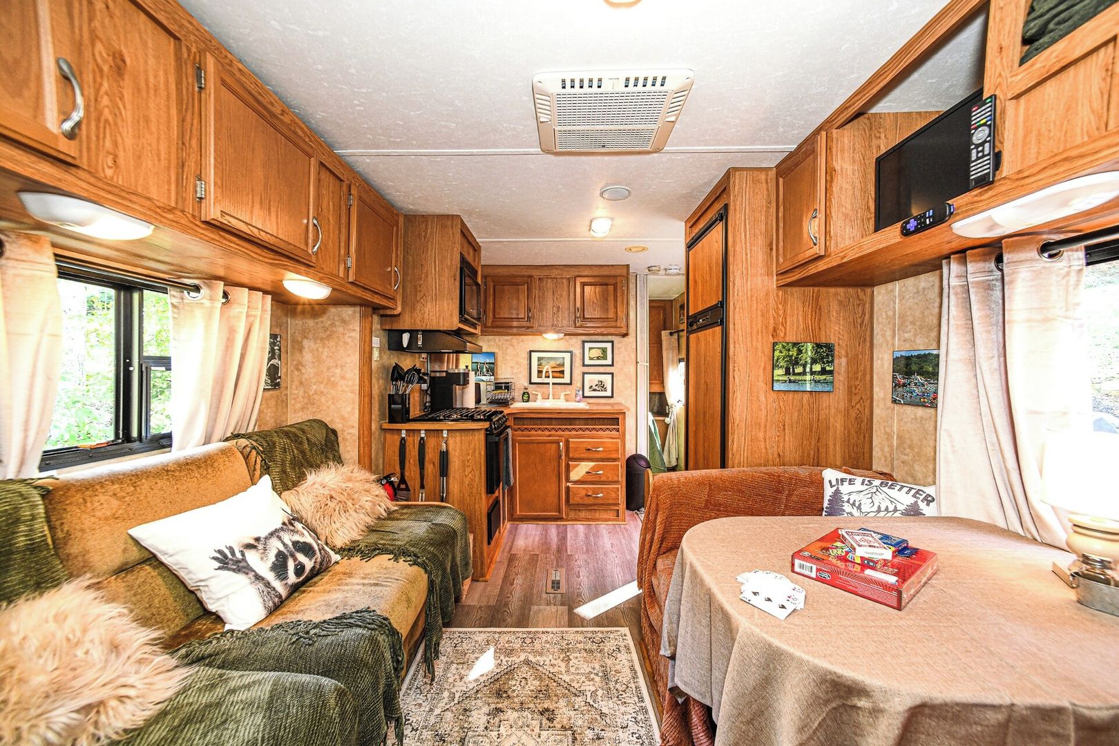 Interior compacte d'una autocaravana amb cuineta, zona de menjador i saló amb sofà i taula.