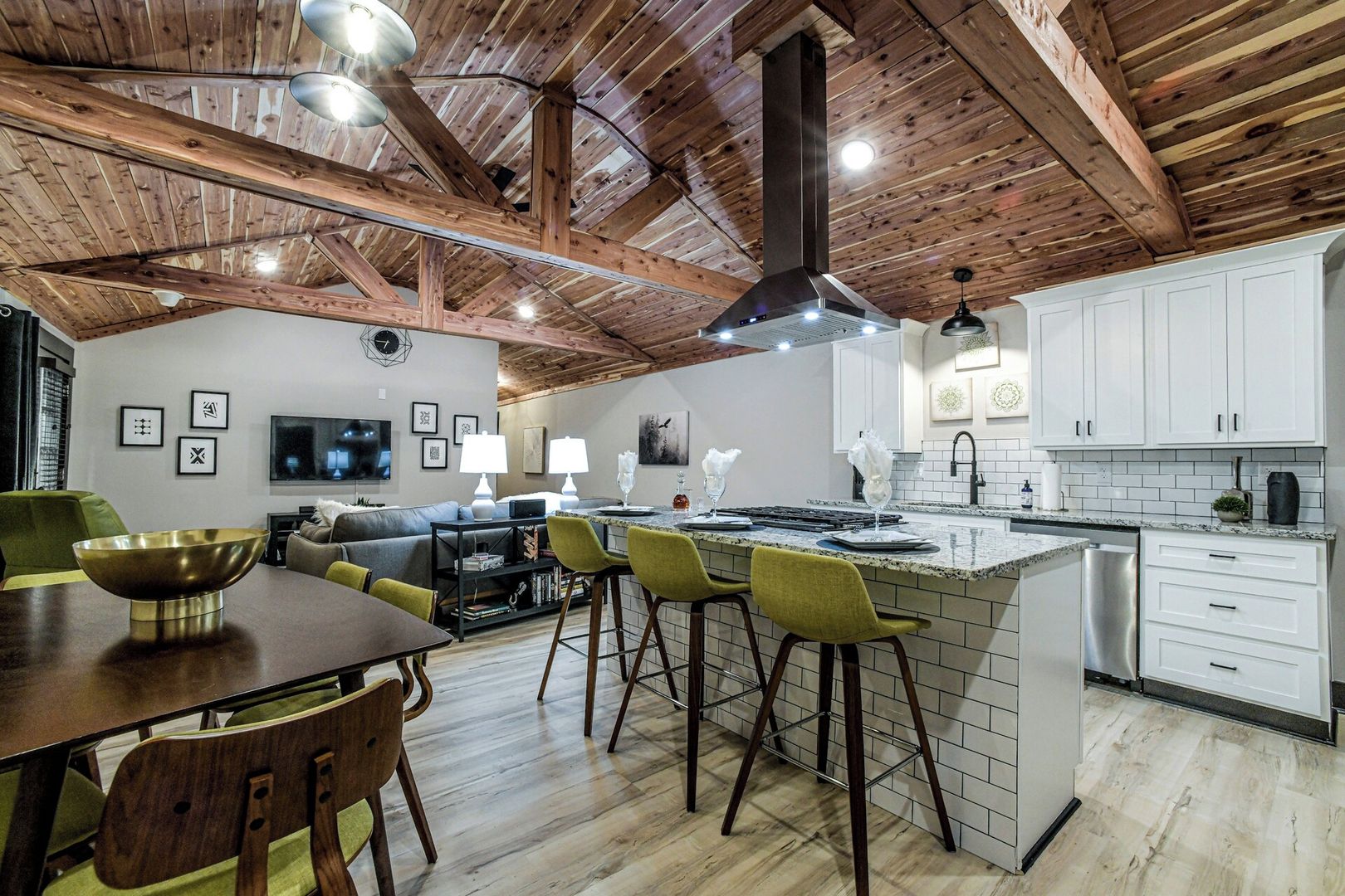 A modern kitchen with white cabinets, a stainless steel dishwasher, and a wooden ceiling.