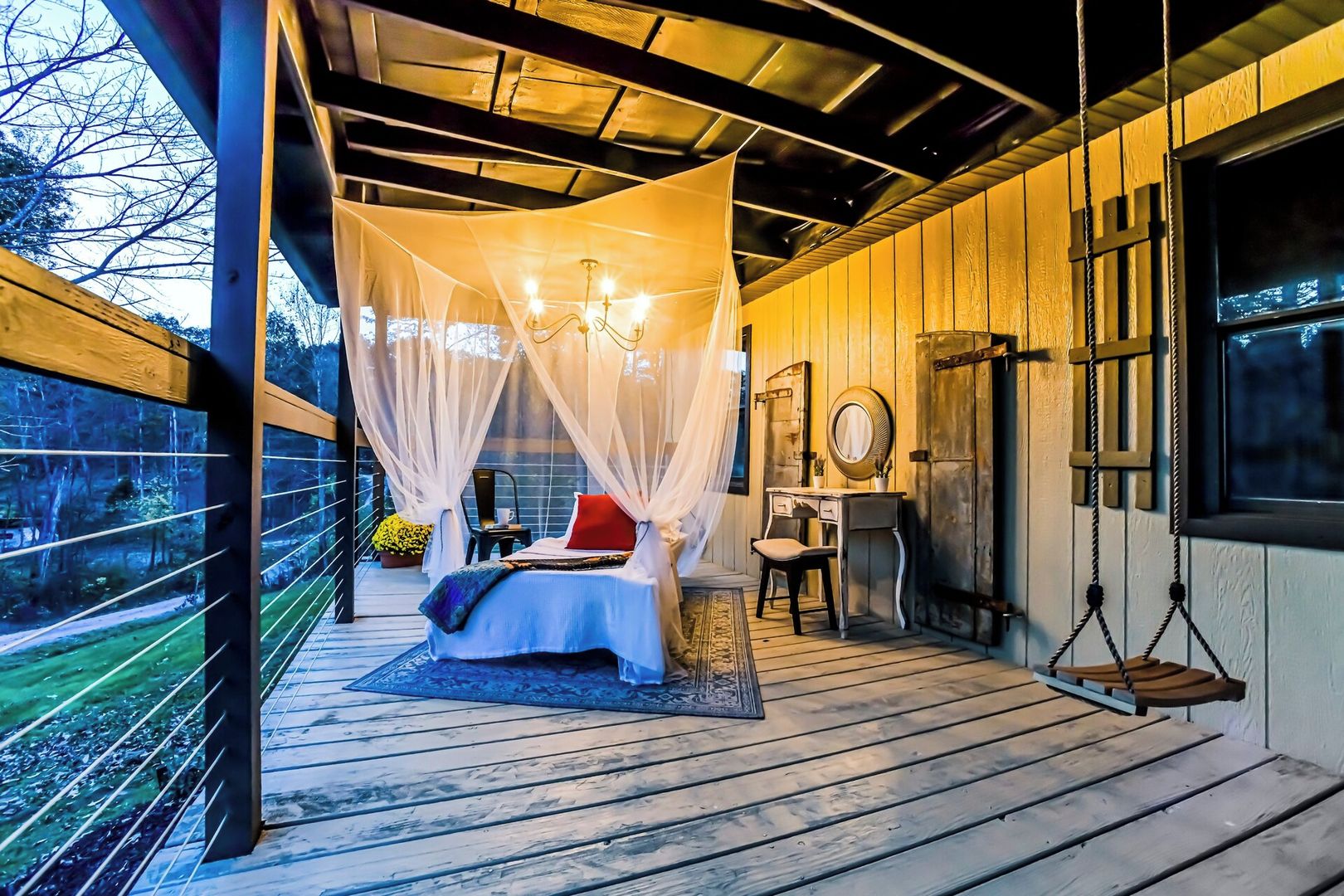 Een slaapkamer met hemelbed, bureau en schommelstoel.