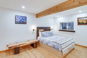 A bedroom with a bed, a bench, a window, and two wall-mounted lights. - Belgrade Lower-Level Apt w/ Sauna, Pet Friendly (Belgrade)