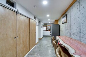 Un couloir mène à une cuisine qui comprend un coin repas avec une table et des chaises.