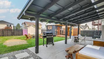 An outdoor patio area with a grill, seating, and a covered section.