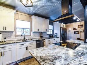 A modern kitchen with white cabinets, a built-in oven, and a large island with a stovetop. - Hill-Billy Hilton Cabin near Mammoth Cave and Nolin Sleeps 16 (Clarkson)