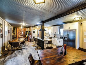 A spacious kitchen with a dining area, featuring a wooden table and chairs, a built-in oven, and a refrigerator.