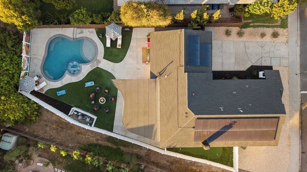 Vista aérea de una propiedad residencial con piscina, zona de estar exterior y un porche cubierto.