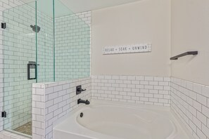 A modern bathroom with a glass shower enclosure, a white bathtub, and a wall-mounted sign. - 3-bedroom house in adorable Mesa with cool AC breeze (Mesa)