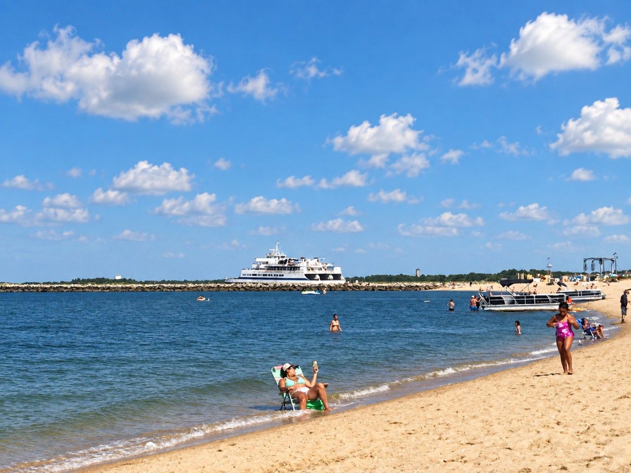 Une plage où un grand navire de croisière est amarré, le ciel est dégagé et les gens profitent de la mer.