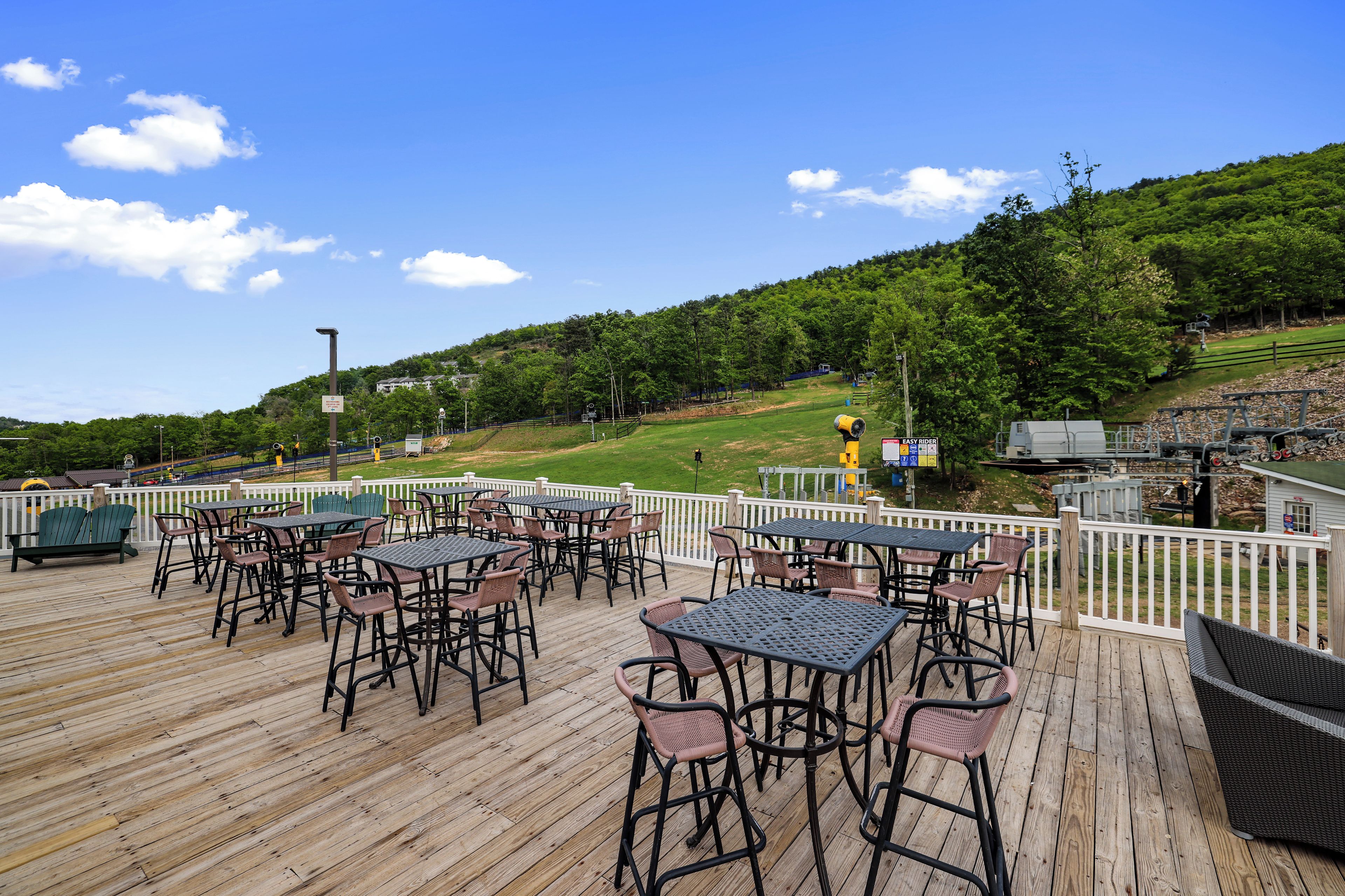 A wooden deck with outdoor seating and a view of a green landscape.