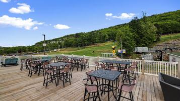 A wooden deck with outdoor seating and a view of a green landscape.