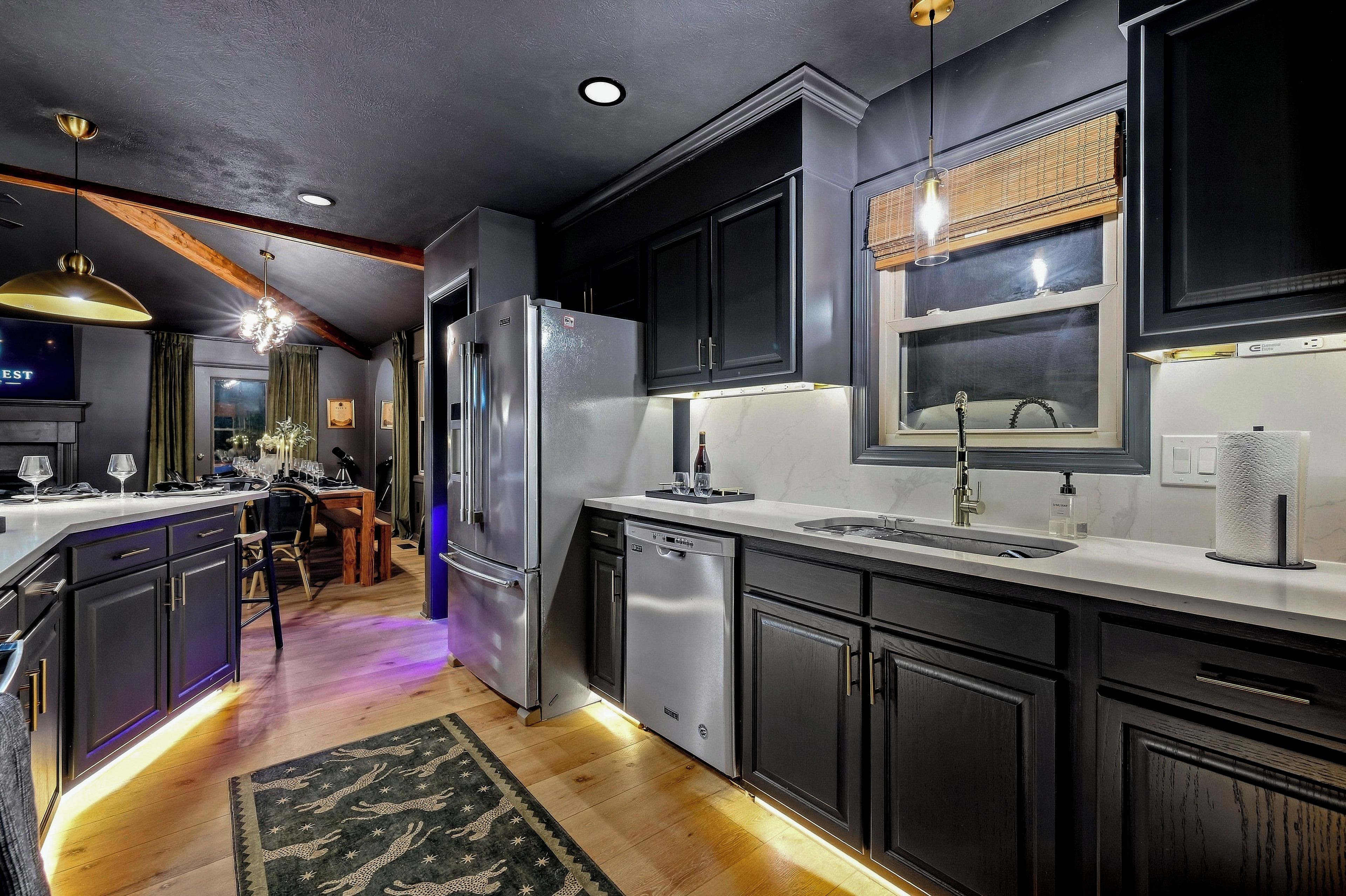 A modern kitchen with dark cabinetry, stainless steel appliances, and a central island.