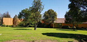 A well-maintained grassy area with trees and a building with a tiled roof.