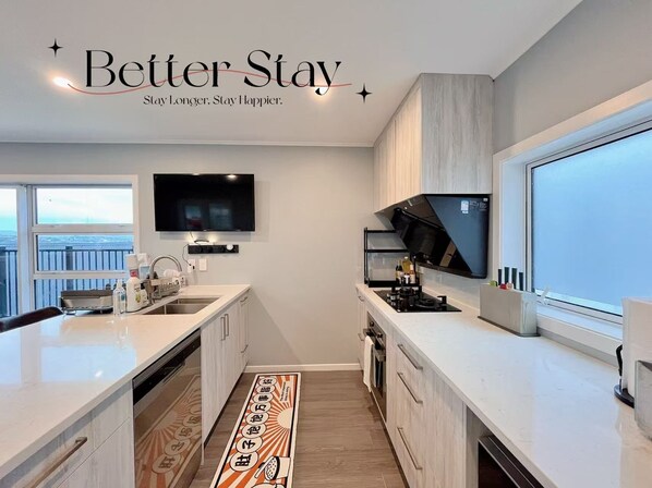 A modern kitchen with a large island, built-in appliances, and a large window.