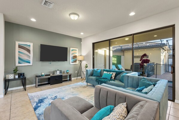 A modern living room with a flat-screen TV, a sofa set, a coffee table, and a side table with decorative items. - South-Facing Pool • Lazy River • Arcade Game Room • Gated Resort • Near Disney (Four Corners)
