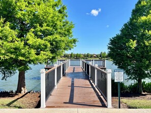 A wooden boardwalk leading to a body of water, surrounded by trees and a warning sign. - South-Facing Pool • Lazy River • Arcade Game Room • Gated Resort • Near Disney (Four Corners)
