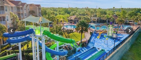 A water park with multiple slides and pools, surrounded by residential buildings and greenery.