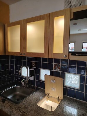 A kitchen with wooden cabinets, a stainless steel sink, and a tiled backsplash. - A minimalist and functional Mexican-style loft in the heart of Coyoacán (Ciudad de México)