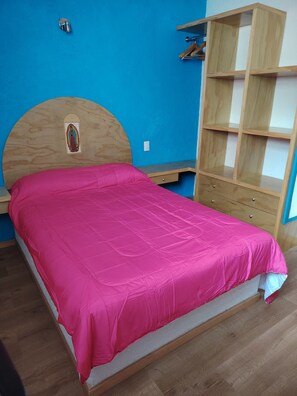 A bedroom with a bed, a wooden headboard, a blue wall, and a wooden wardrobe. - A minimalist and functional loft in the Mexican style, located in the heart of Coyoacán (Ciudad de México)