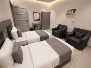 A hotel room with two beds, a desk, a chair, and an air conditioning unit. - Luxury Modern Apartment  Near Alharam  And Airport (Madinah)