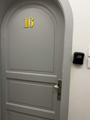 A gray door with the number 16, a doorbell, and a wall-mounted intercom. - Luxury Modern Apartment  Near Alharam  And Airport (Madinah)