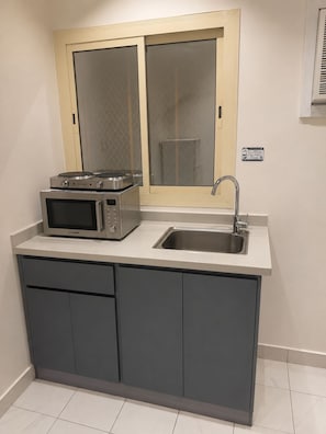 A compact kitchen with a microwave, toaster, and sink. - Luxury Modern Apartment  Near Alharam  And Airport (Madinah)
