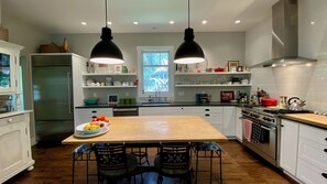 A modern kitchen with a central island, two pendant lights, and a window providing natural light. - Elegant 2-bedroom home in serene garden close to downtown (Paonia)