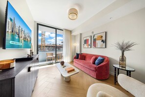 Ein modernes Wohnzimmer mit einem roten Sofa, einem Couchtisch, einem Fernseher und Kunstwerken an der Wand.