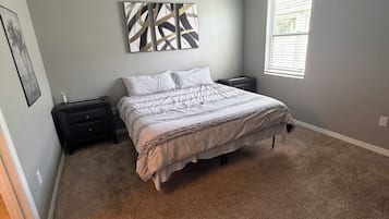 Un dormitorio con cama, mesita de noche, una obra de arte en la pared y una ventana.