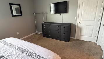 Un dormitorio con cama, cómoda, televisor y puerta.