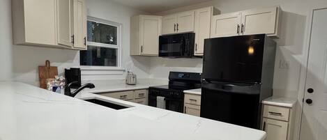 A modern kitchen with white cabinetry, a black refrigerator, and a large island.