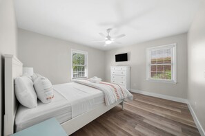 A bedroom with a bed, a nightstand, a dresser, a ceiling fan, and two windows with blinds. - GSU Hospital Haven: located near everything! (Statesboro)