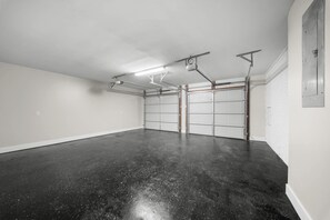 A clean, empty garage with a black floor, white walls, and a white garage door. - GSU Hospital Haven: located near everything! (Statesboro)