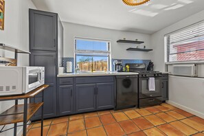 A modern kitchen with grey cabinets, a built-in oven, a microwave, and a window with blinds. - Casita Anita Historic Adobe Near Downtown Tucson (Tucson)