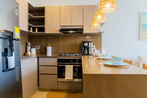 A modern kitchen with a built-in oven, a coffee machine, and a dining area with a table and chairs. - Sereno Stays · 3BR Apartment, Santa Marta (Unknown)