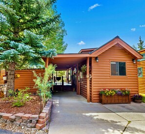 A log cabin with a covered porch, a stone wall, and a tree. - Charming Breckenridge cabin with unobstructed mountain views on the  Blue River (Breckenridge)
