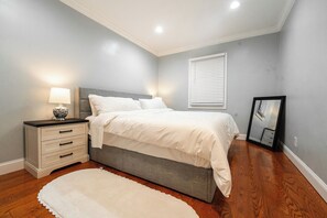 Un dormitorio con cama, mesita de noche, lámpara y espejo.