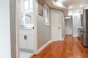 Una cocina con muebles blancos, un refrigerador de acero inoxidable y piso de madera.