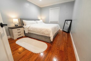 A bedroom with a bed, bedside tables, a nightstand, a mirror, and a rug. - Modern Apartment Near Union Market & NoMa (Washington)