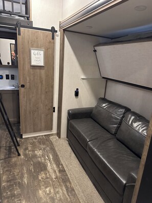 A compact living space with a kitchenette, a leather sofa, and a door with a 'hello sweet cheers' sign. - Spacious countryside retreat in peaceful Paso Robles (Paso Robles)