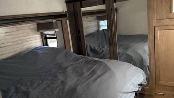 Un dormitori amb dos llits, ambres de fusta i un sostre amb ventilació.