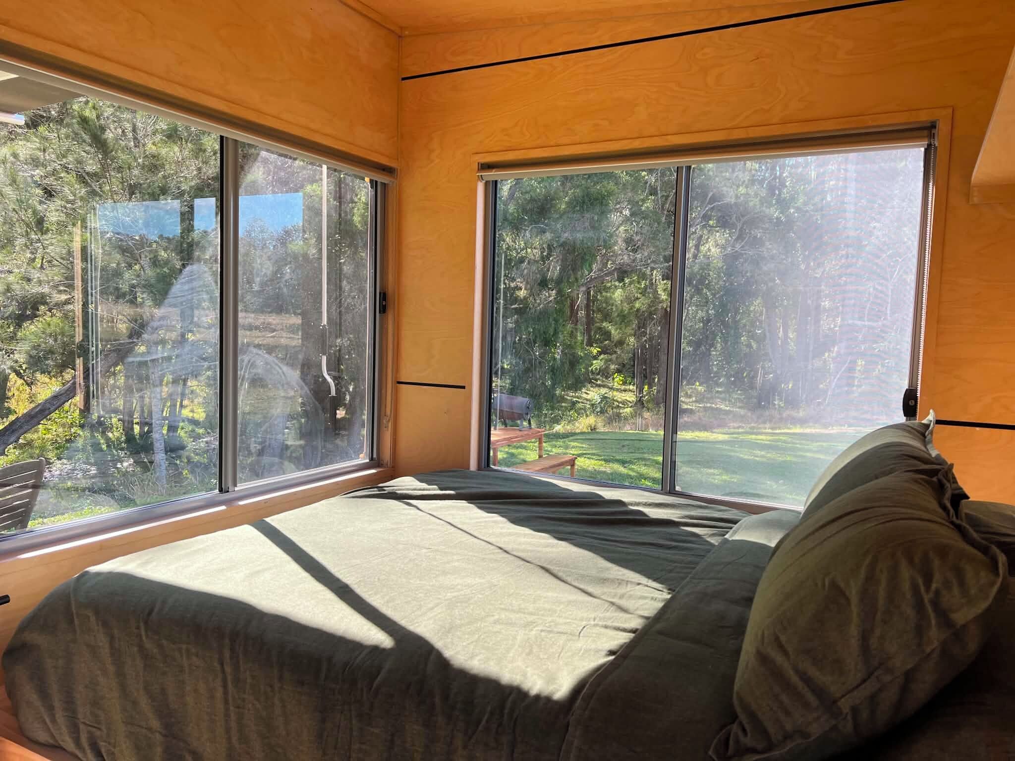 Ein Zimmer mit einem Bett, großen Fenstern und Blick auf einen Garten.