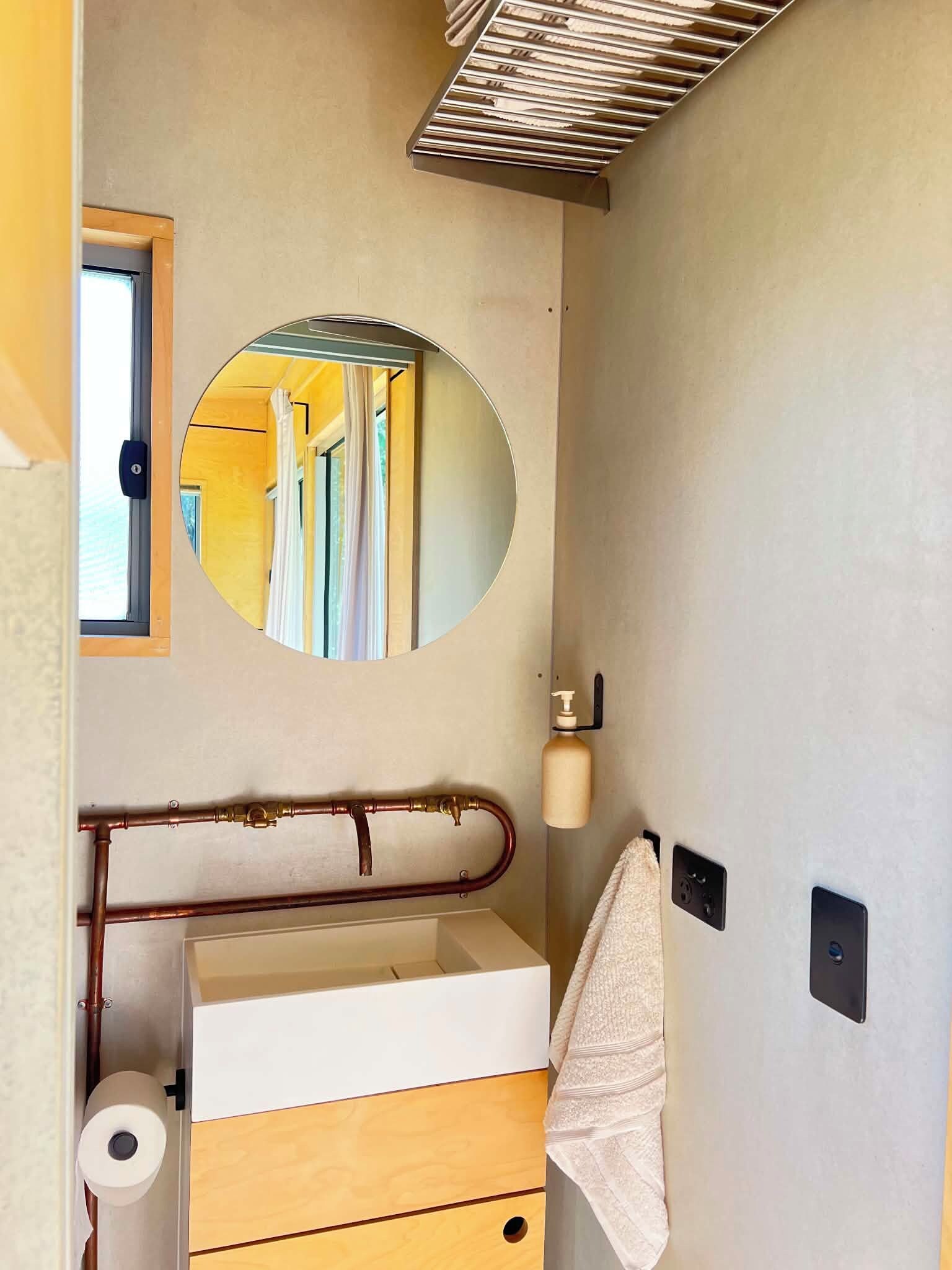 Een badkamer met spiegel, handdoekhouder, toiletpapier en een douchegordijnstang.