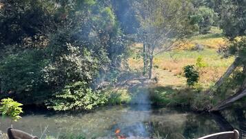 A campsite with a fire pit and two chairs by a river.