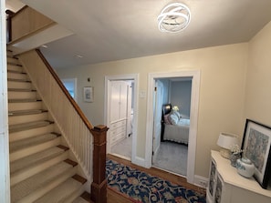 A staircase leading to a bedroom with a bed, a dresser, and a nightstand. - Classic Cape with Modern Cottage Charm (Horseheads)