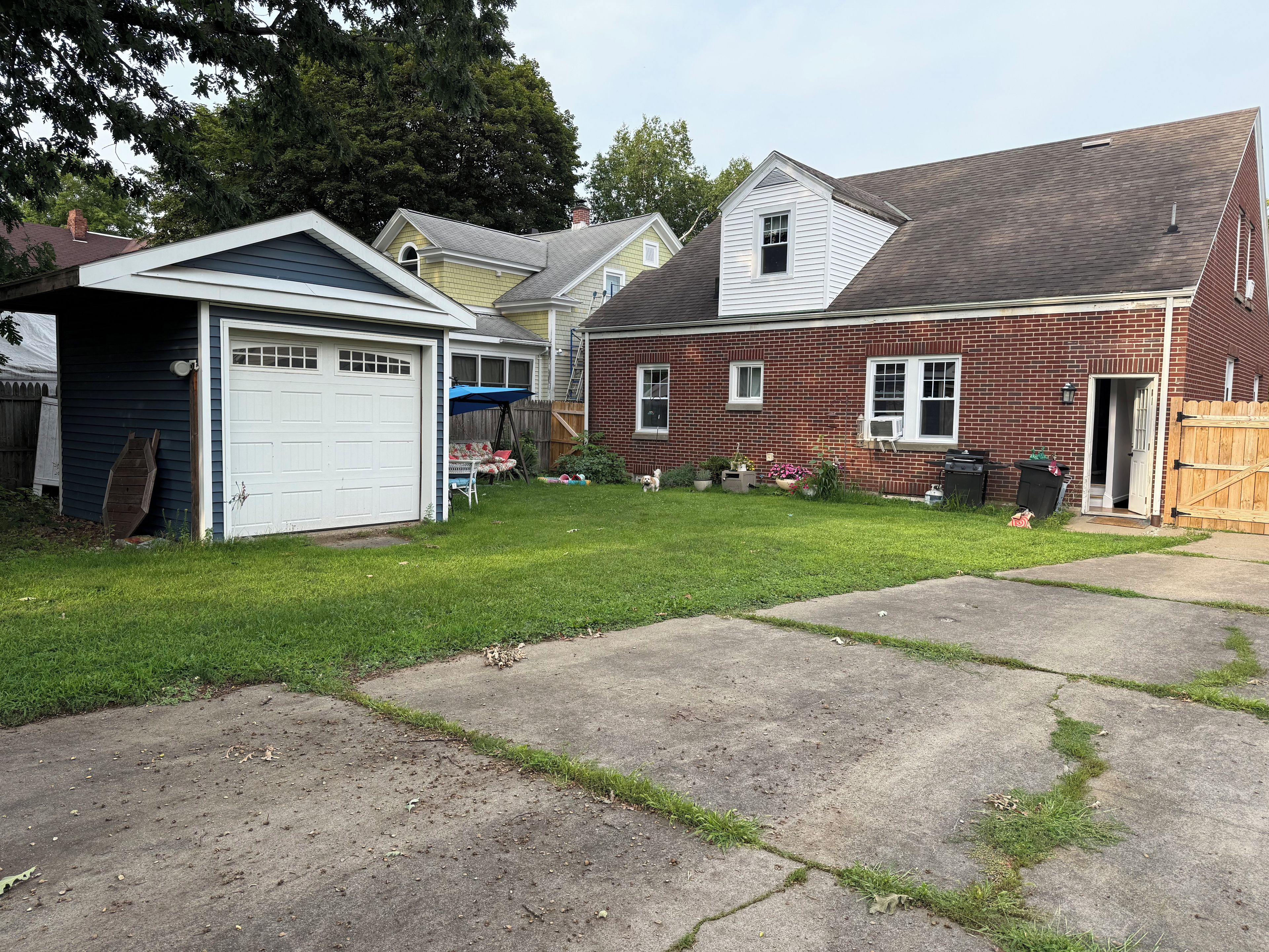 A residential property with a garage, a covered patio, a brick house, and a fenced yard.