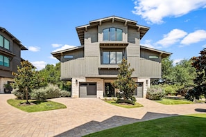 A two-story house with a stone foundation, a garage, and a driveway leading to the entrance. - Luxe 3BR Lake Stay | BBQ | Firepit | Pickleball (Spicewood)