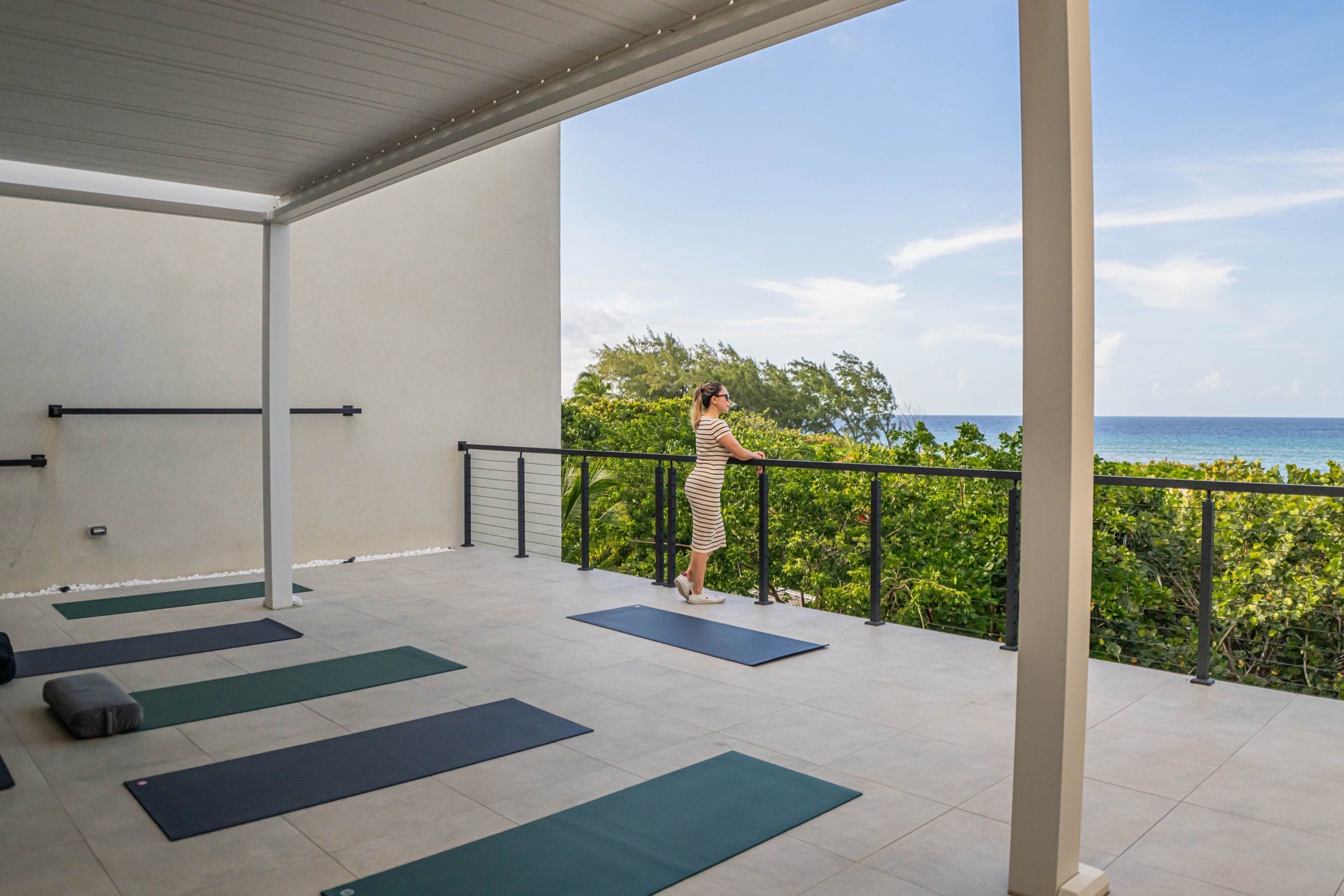 Un balcone con tappetini da ginnastica e un corrimano, affacciato su uno specchio d'acqua.