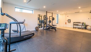 Una palestra con tapis roulant Rogue, attrezzature per sollevamento pesi e manubri.