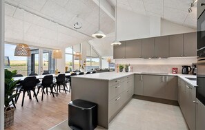 A modern kitchen with a large island, grey cabinetry, and a view of the outdoors. - Cozy home in Bogense with sauna (Bogense)